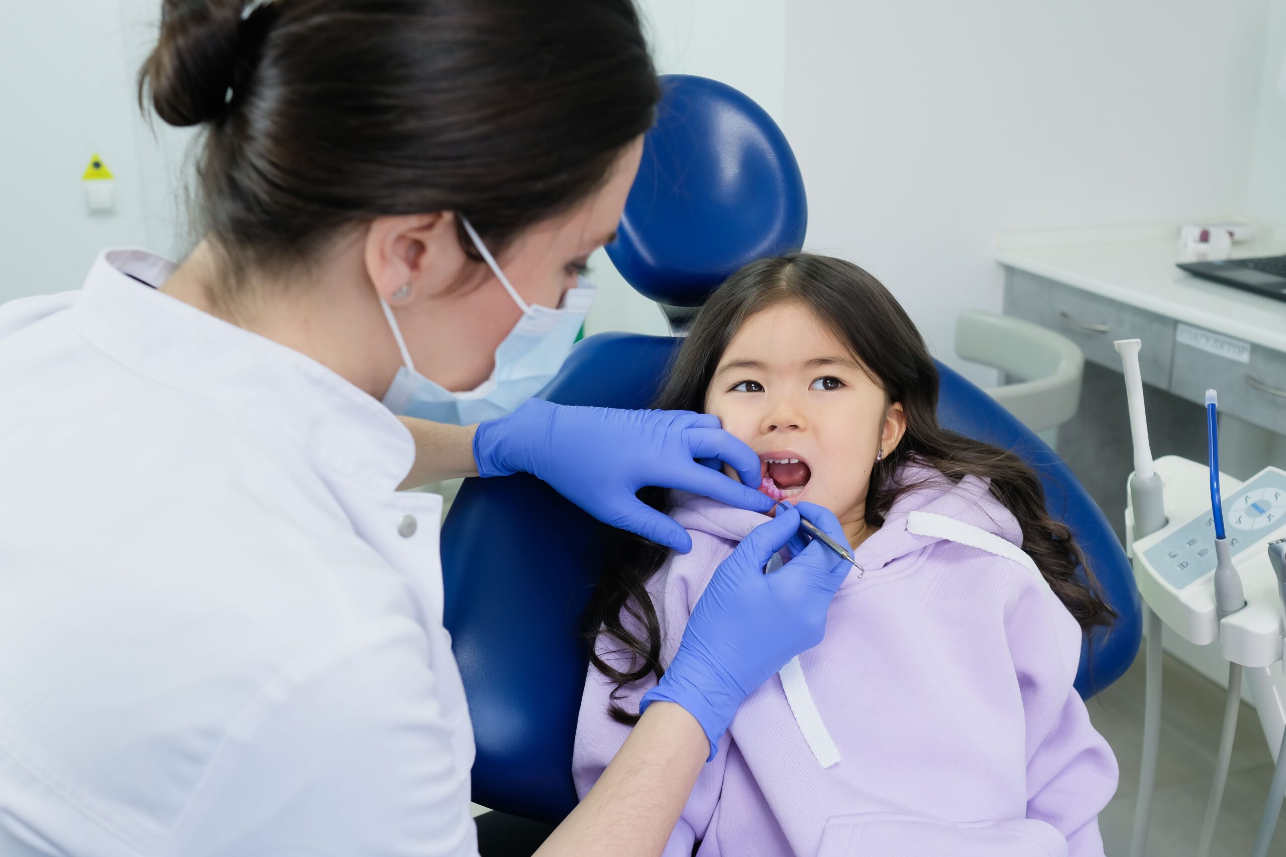 Young girl receives dental checkup from a female dentist in a clinic.

