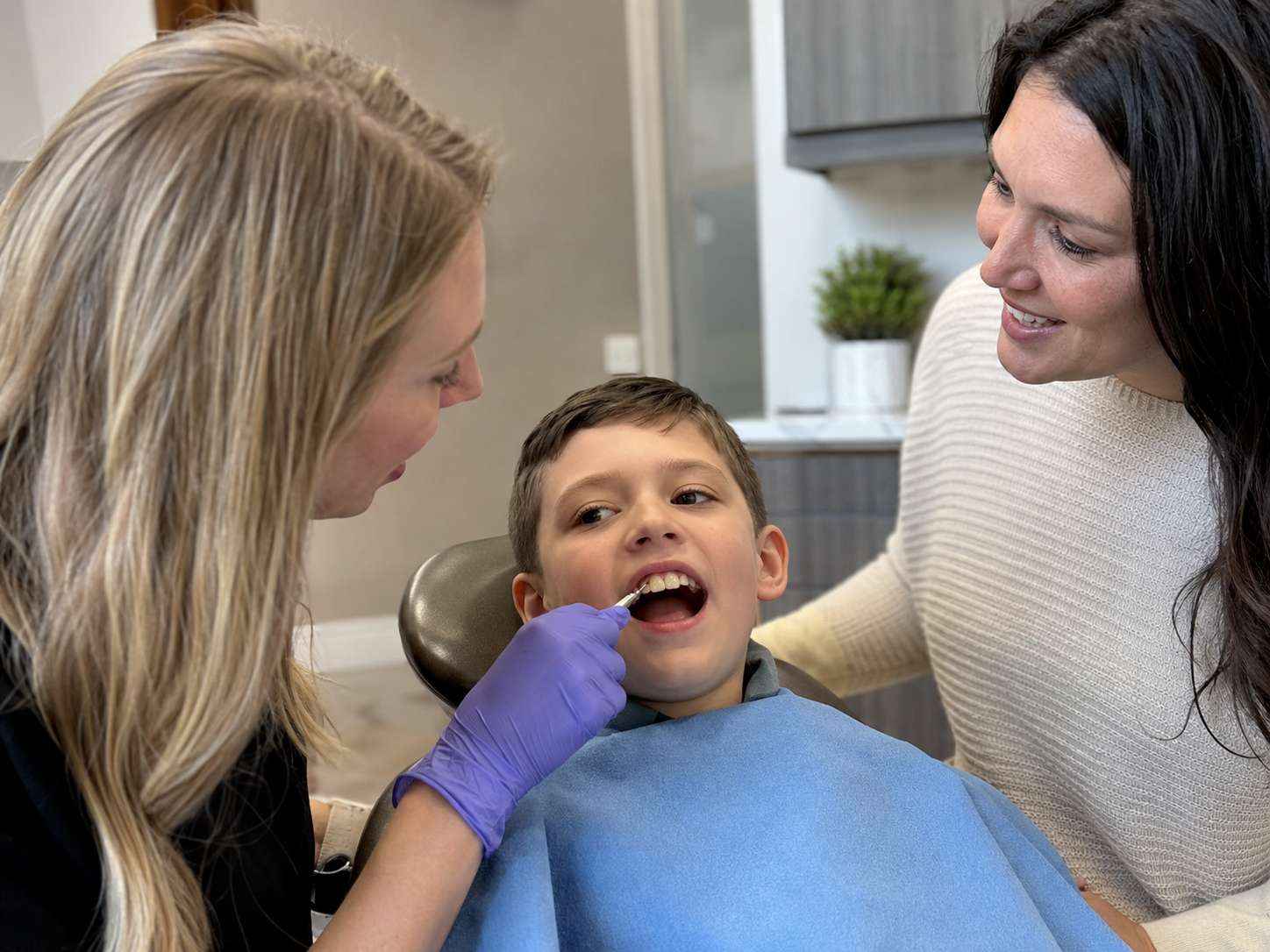 Pediatric dentist showing a parent the color difference between a child’s permanent teeth and baby teeth.